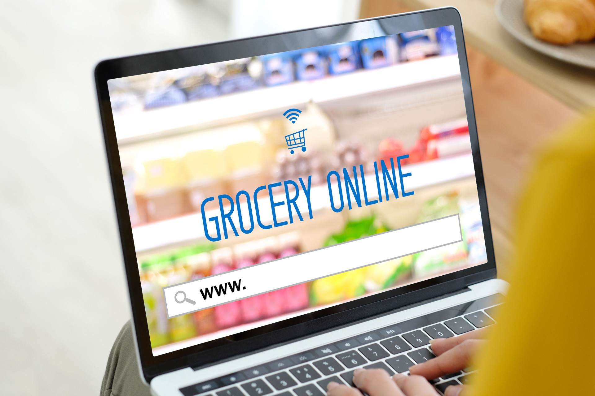 Close-up of a laptop showing a colorful grocery website with the words ‘Grocery Online’ on the screen, representing online grocery shopping.